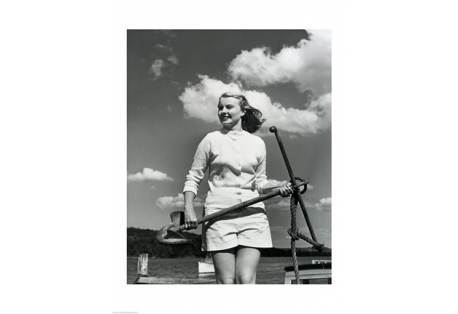 Young woman standing on boat, holding anchor